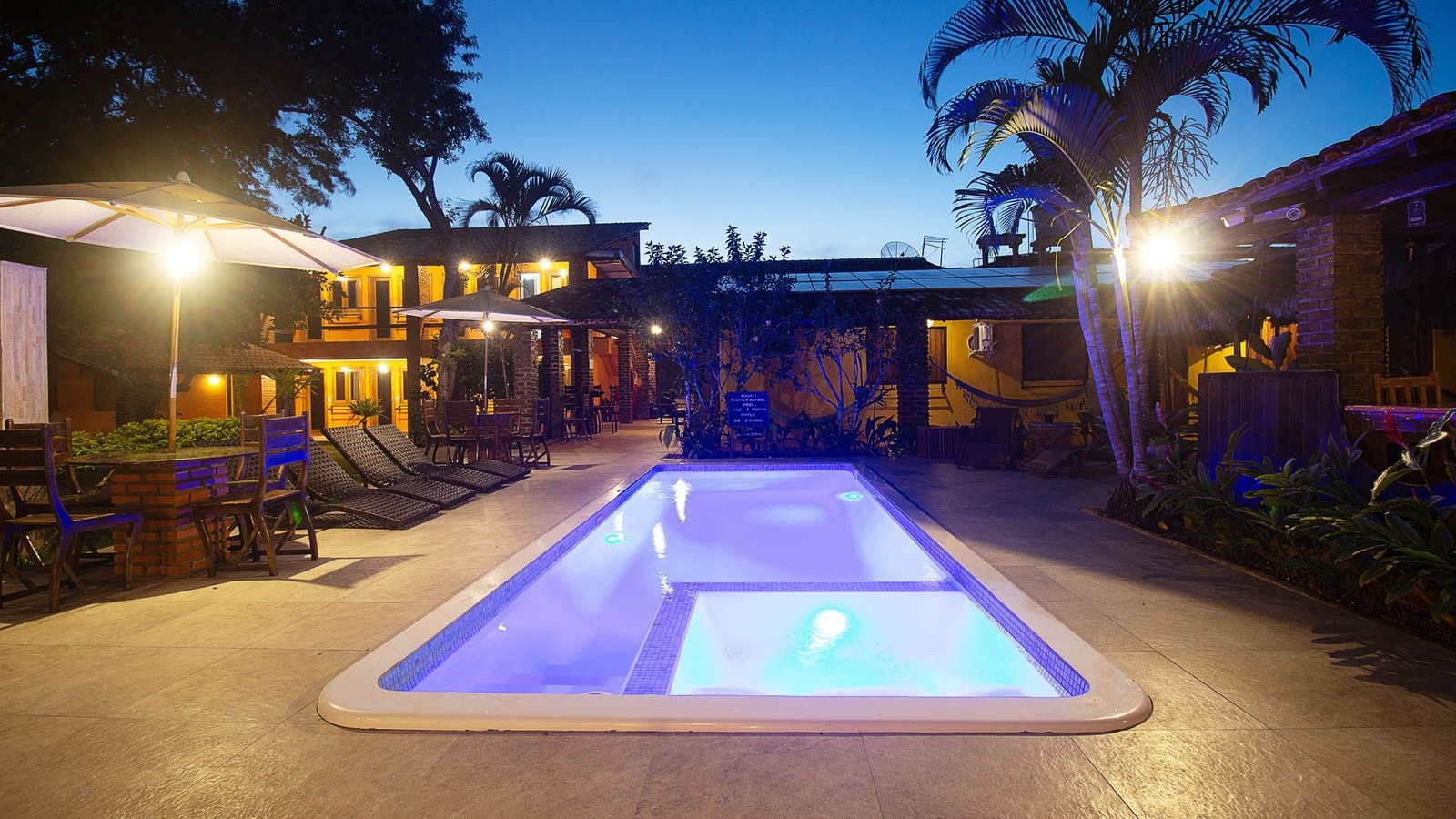 Piscina iluminada da Pousada Cavalo Marinho ao entardecer